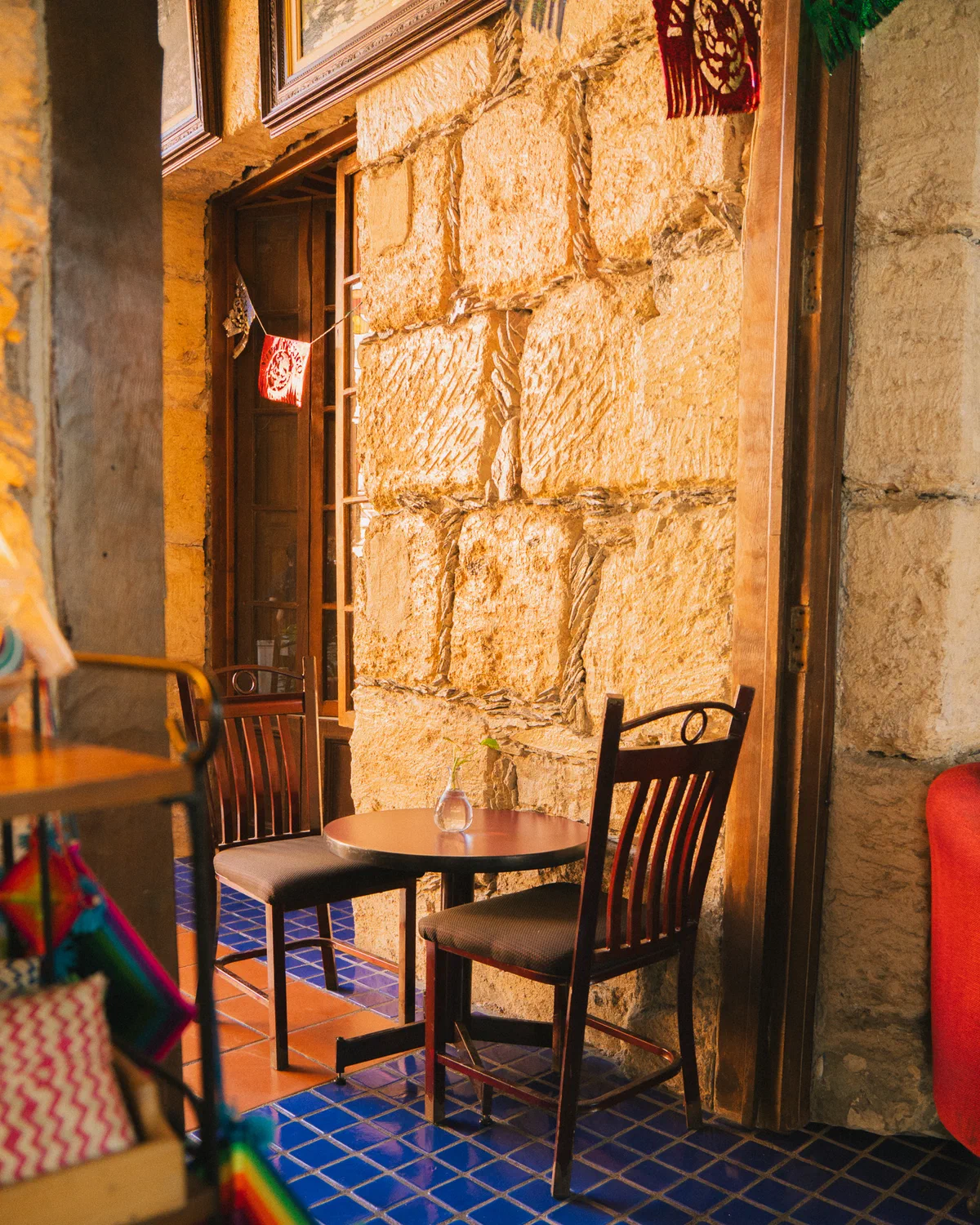 Mesa para dos junto a un muro de piedra iluminado por el sol en la cafetería Audaz