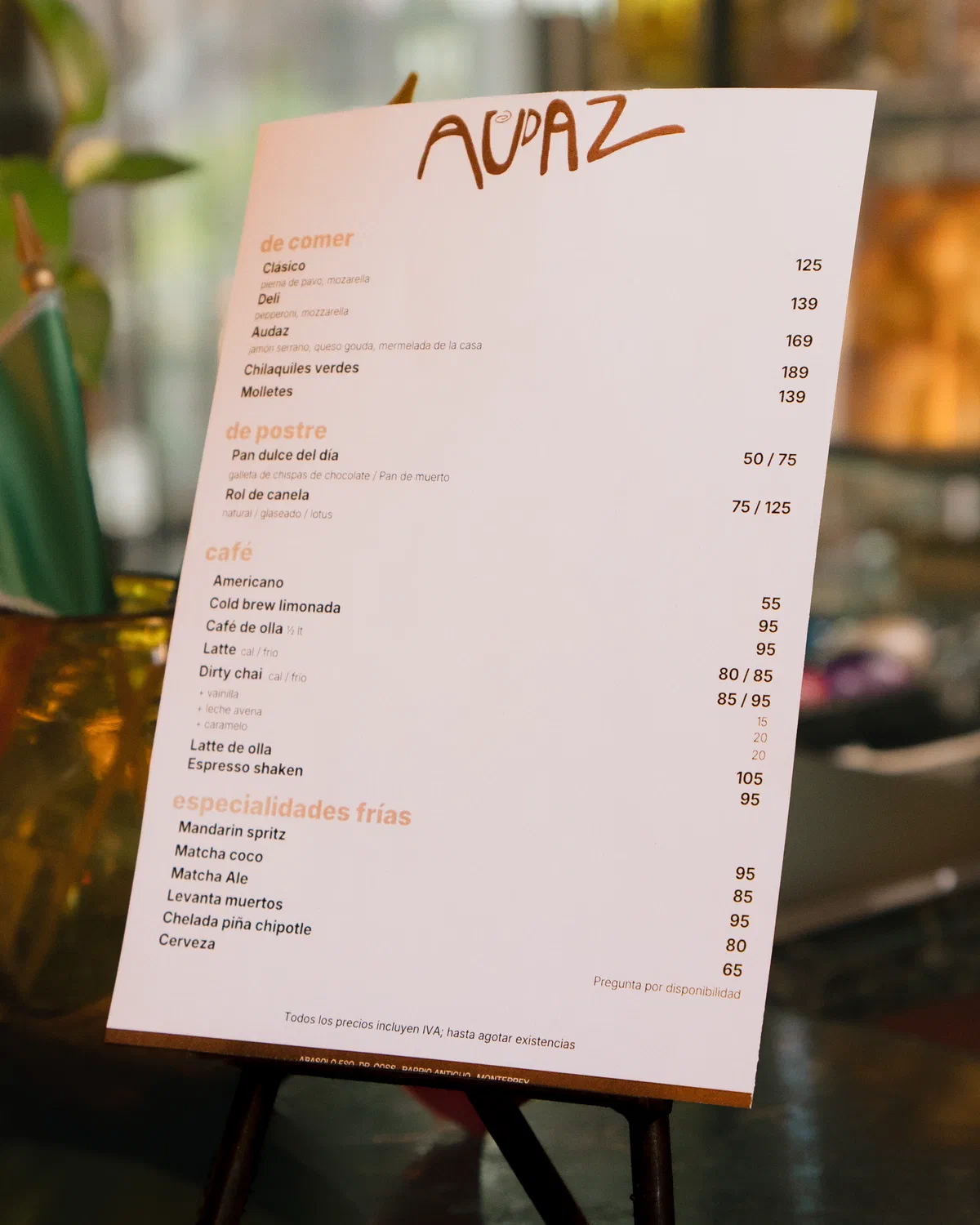 Menú de bebidas y alimentos de la cafetería Audaz en un atril