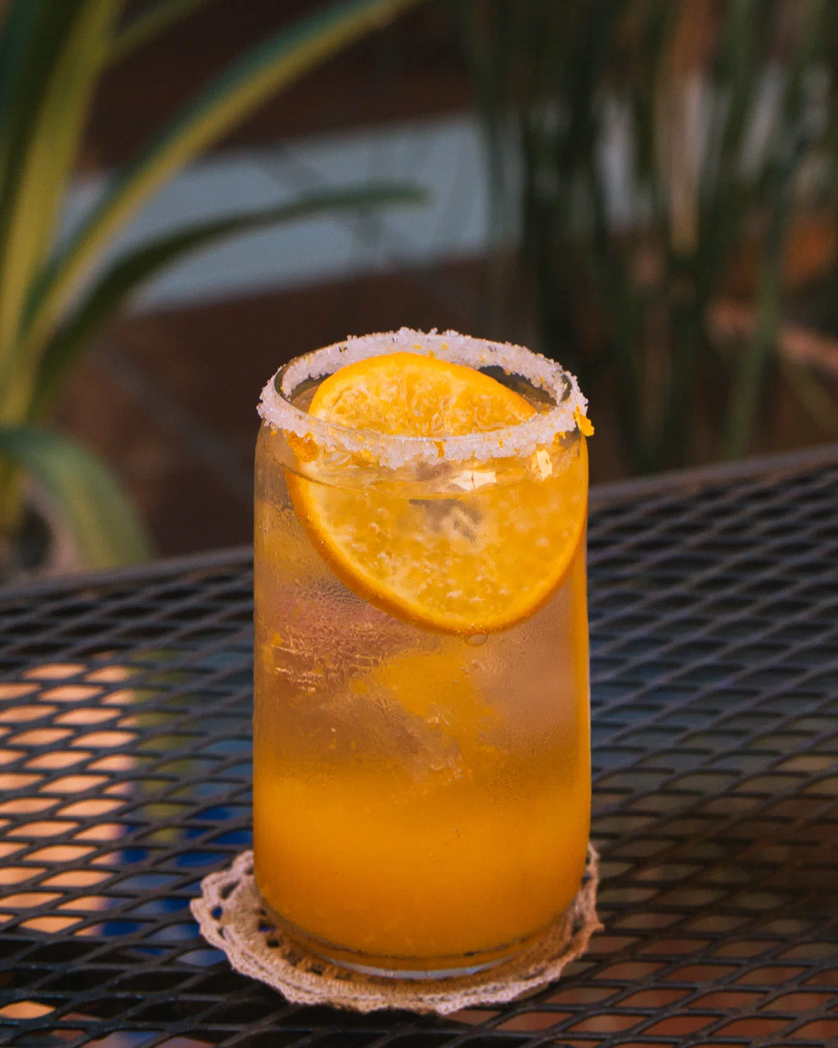 Bebida de naranja escarchada con rodaja de naranja sobre mesa de herrería