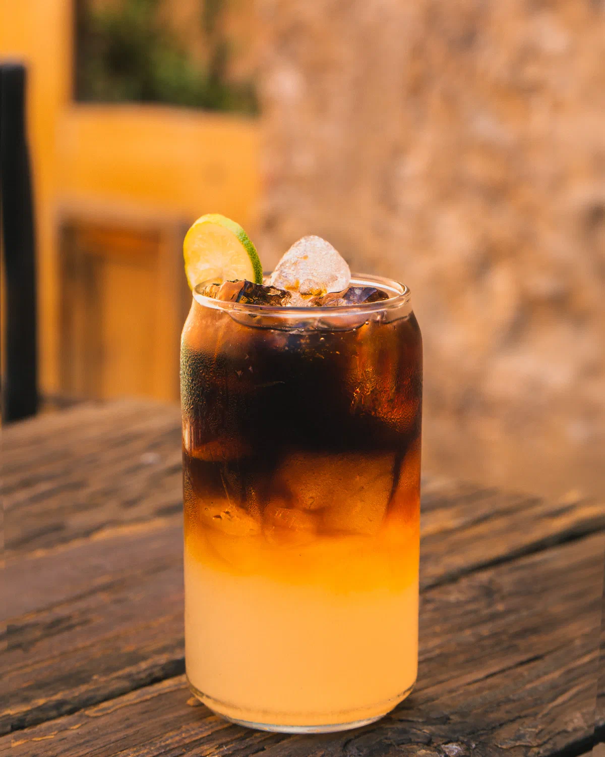 Bebida de café en capas con hielo y limón sobre mesa de madera