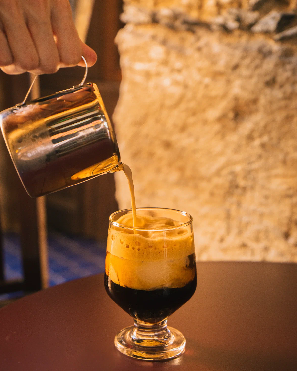 Barista sirviendo una bebida de café en copa de vidrio en Audaz