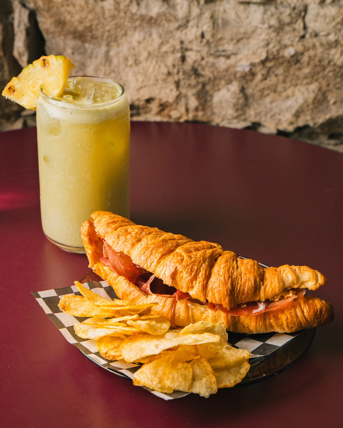 Croissant de jamón con papas fritas y bebida de piña