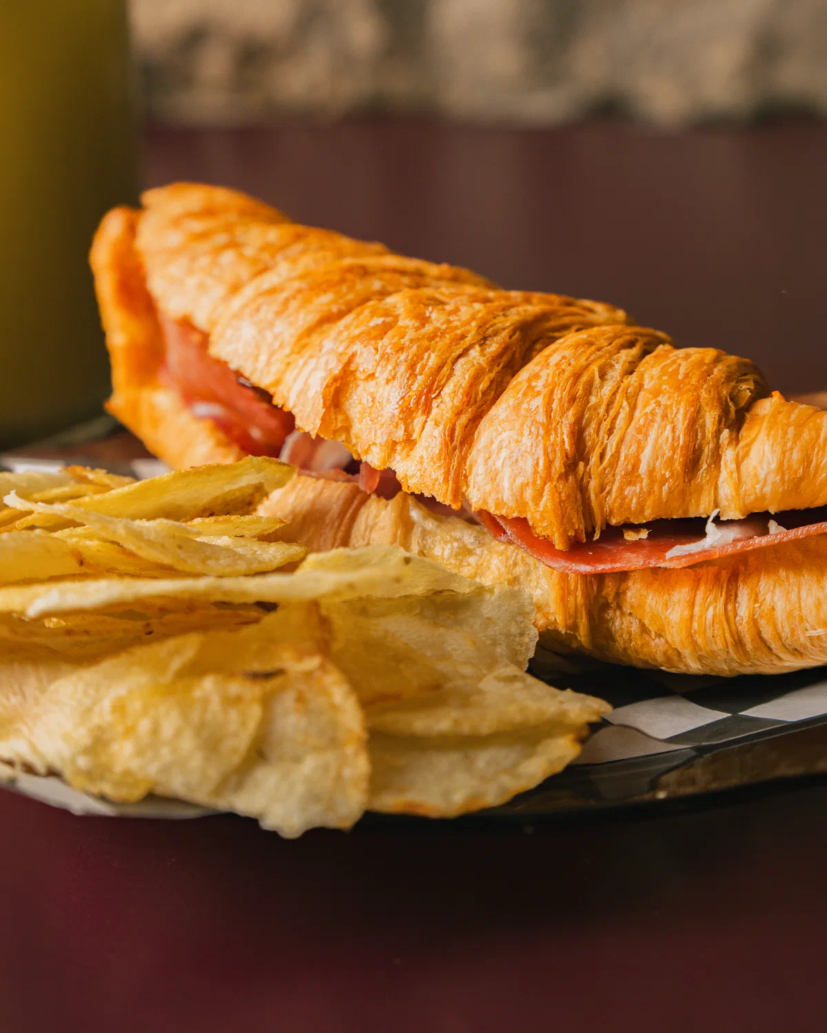 Croissant relleno de jamón en primer plano con papas fritas