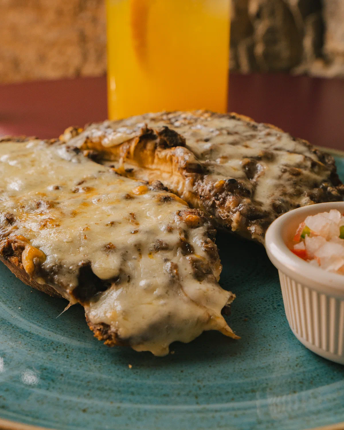 Quesadilla con queso gratinado y pico de gallo en plato de cerámica azul