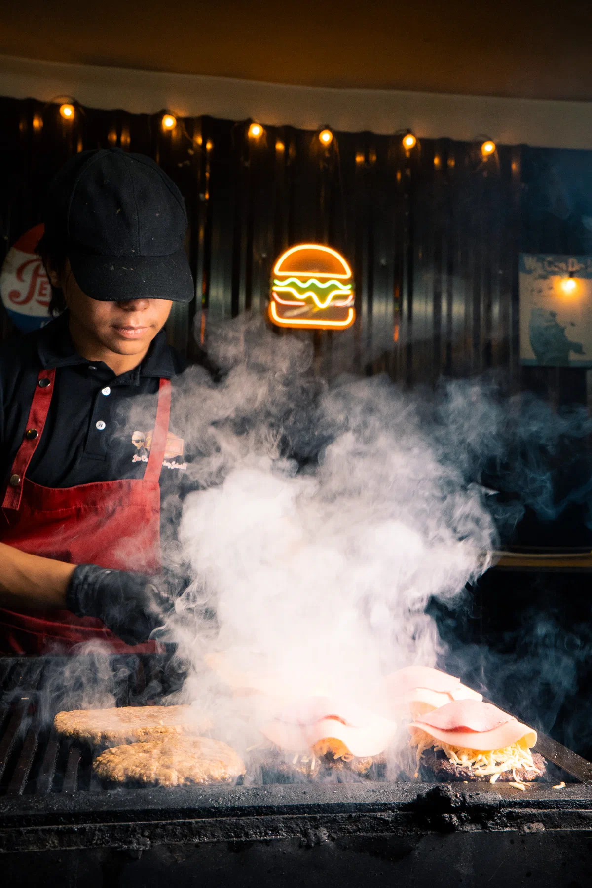 Cocinero de Rossie's Burger asando carne en la plancha entre humo