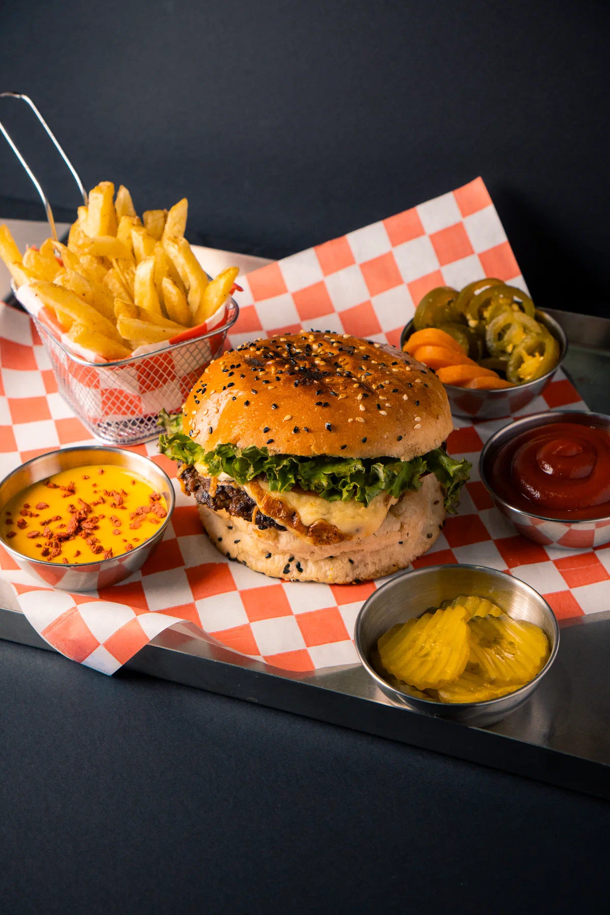 Hamburguesa con papas, chiles, catsup y salsa de queso sobre papel a cuadros