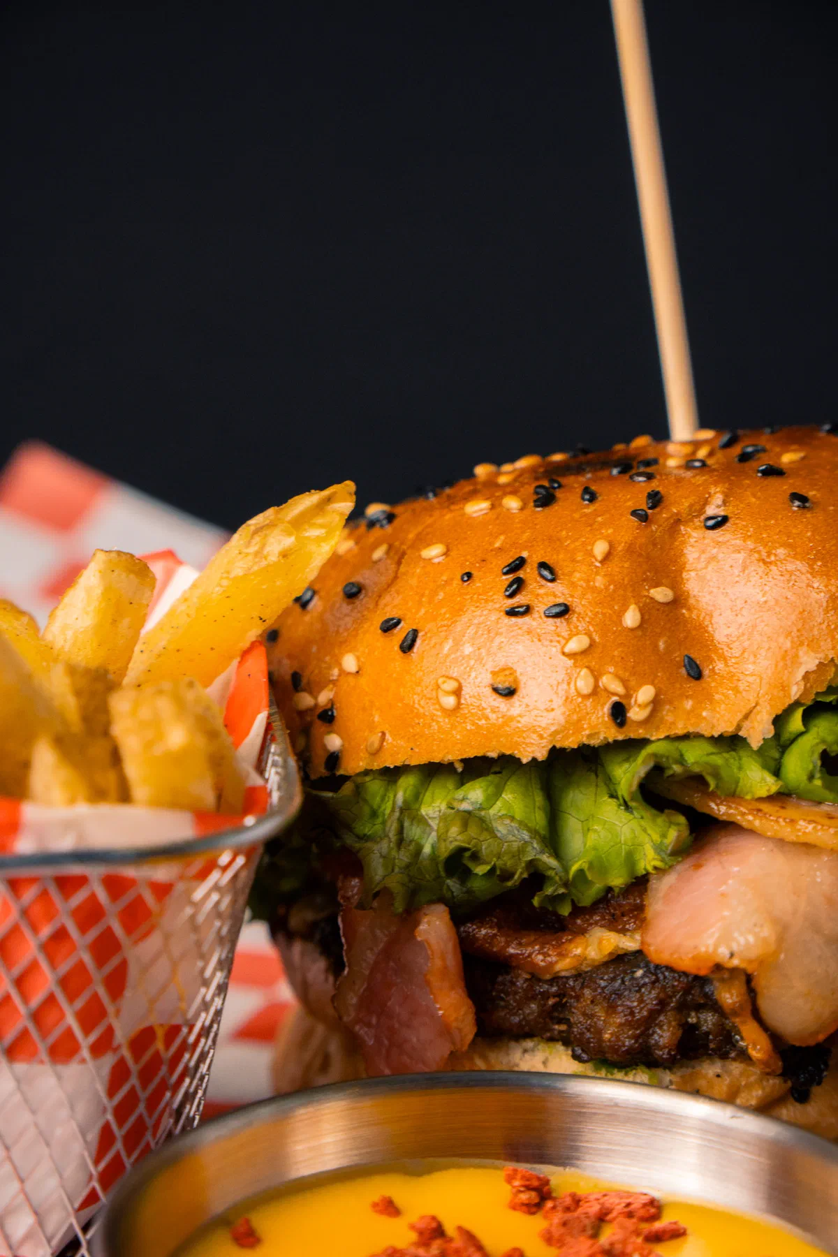 Hamburguesa con tocino junto a papas fritas y salsa de queso