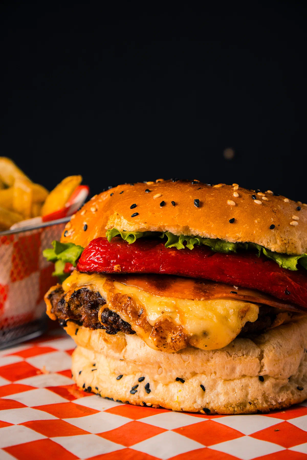 Hamburguesa con pimiento rojo asado y queso derretido sobre papel a cuadros