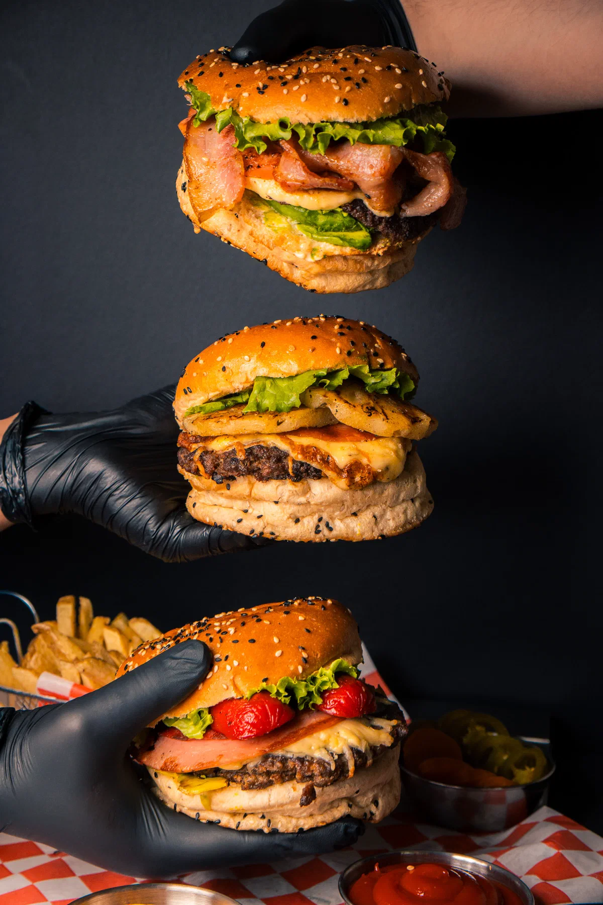 Tres hamburguesas de Rossie's Burger sostenidas con guantes negros