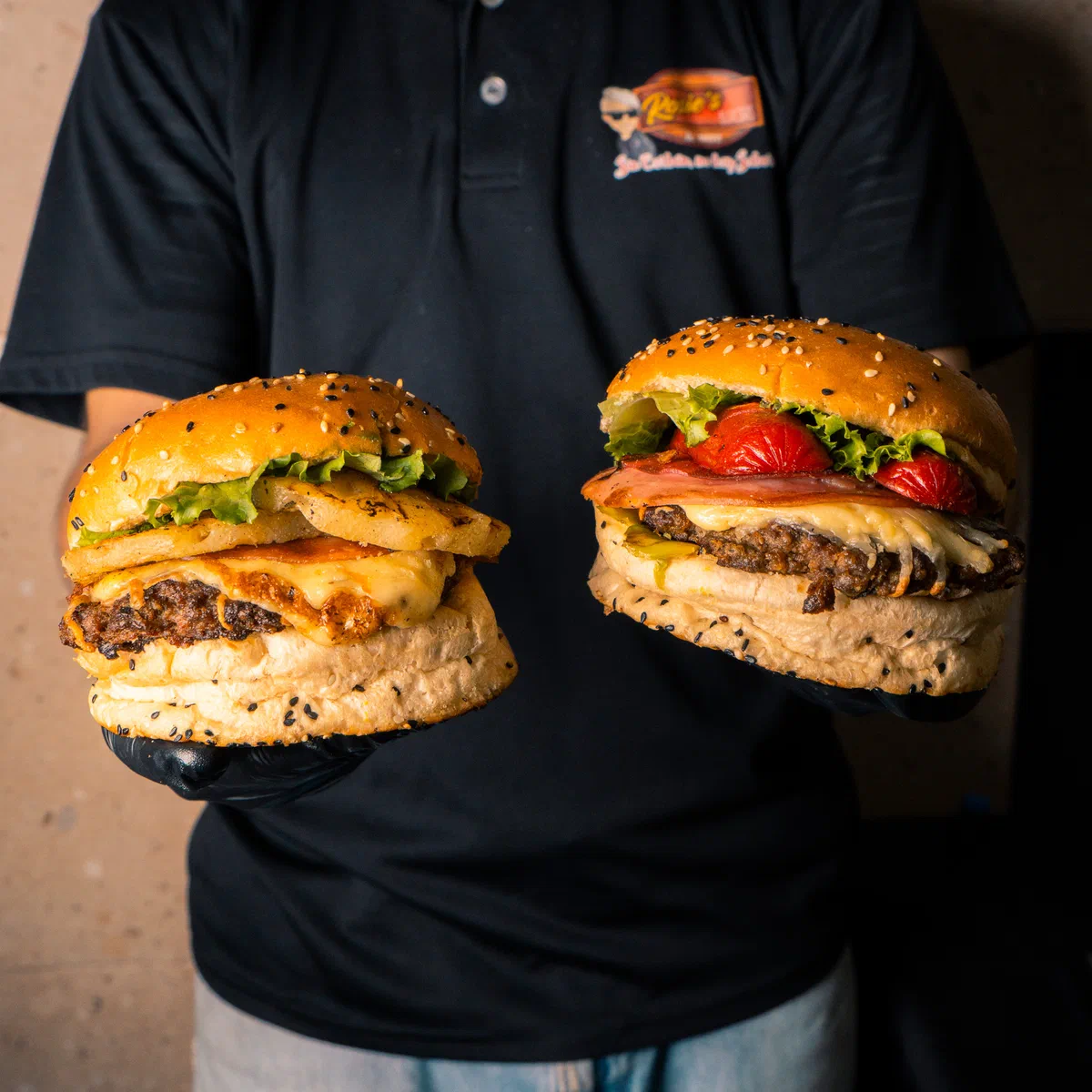 Dos hamburguesas sostenidas por el equipo de Rossie's Burger