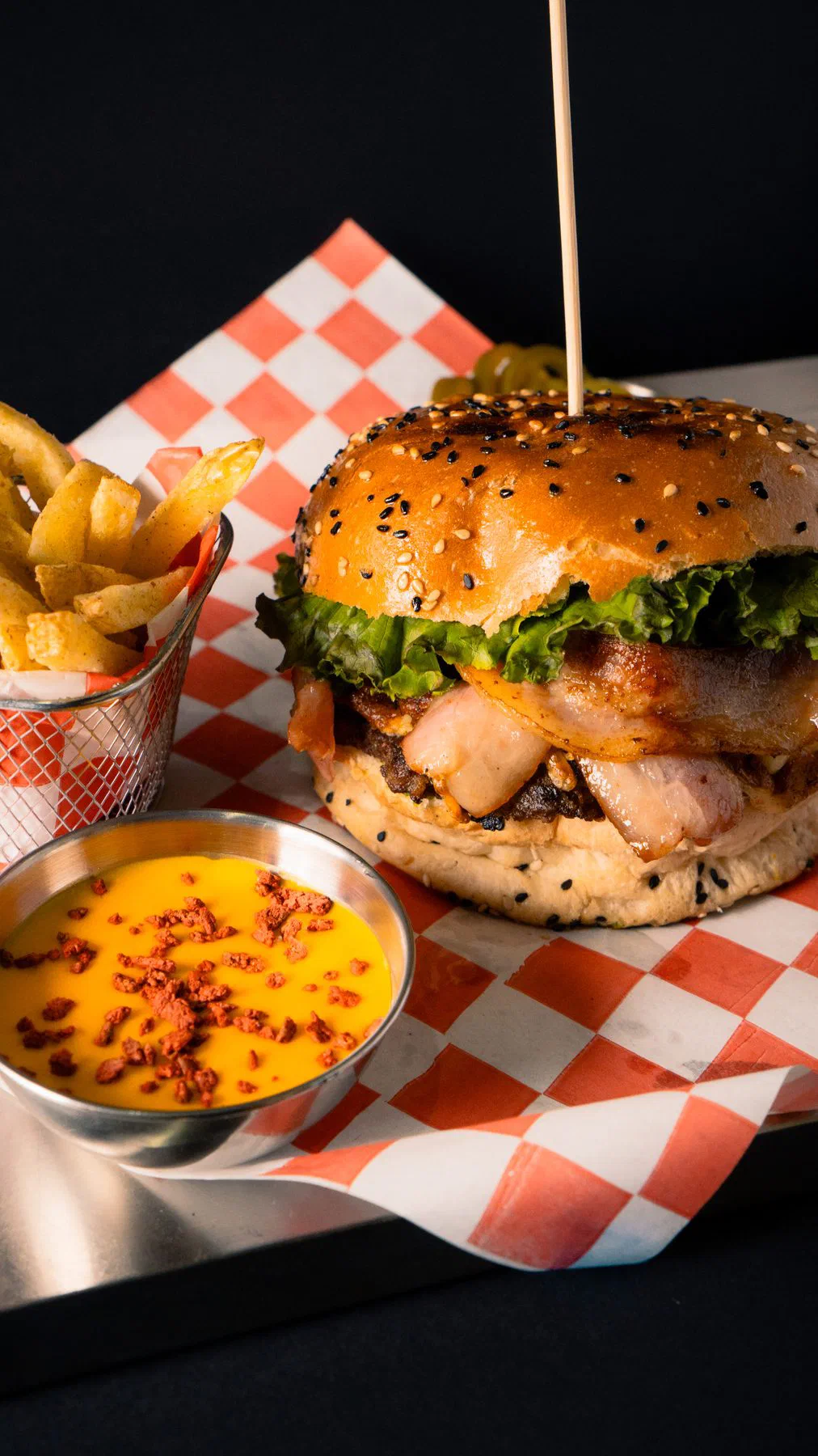 Hamburguesa de Rossie's Burger con papas a la francesa y salsa amarilla, fondo negro